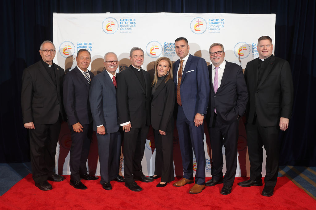 2023 Bishop's Humanitarian Award Dinner Honorees Group photo of 8 individuals on a red carpet in front of a step and repeat.