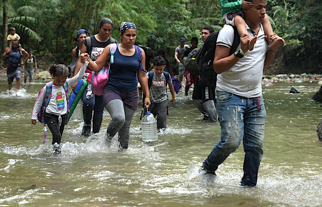 Nearly half of the 400,000 people who slogged through Panama’s Darién Gap so far this year are children. These migrants are shown entering the gap from Colombia. (Photo: Manuel Rueda, Global Sisters Report, via OSV) Adult asylum seekers hold on to their children while crossing the Darien Gap.